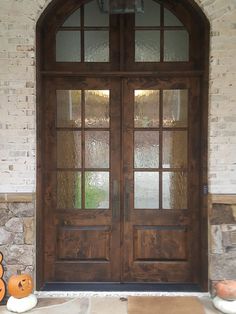 two pumpkins are sitting on the front steps of a house with glass doors and brick walls