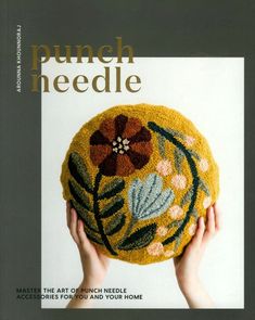 the cover of punch needle magazine featuring a hand holding a yellow round object with flowers on it