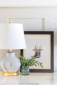 a white lamp sitting on top of a table next to a vase filled with flowers