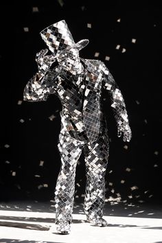 a man is standing in front of a black background with lots of confetti