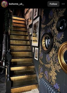 the stairs in this house are decorated with gold and black wallpaper, along with pictures on the walls