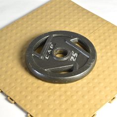 an iron weight plate sitting on top of a yellow mat with white dots around it