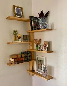 three wooden shelves with books and pictures on them in a corner next to a wall