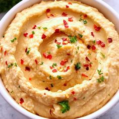 a white bowl filled with hummus and chopped parsley