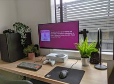 a desk with a keyboard, mouse and monitor on it in front of a window