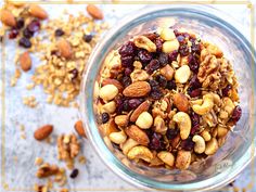 a glass bowl filled with nuts and cranberries on top of a white table