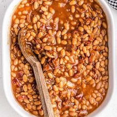 baked beans in a white bowl with a wooden spoon