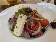 a salad with tomatoes, onions and cheese on a white plate