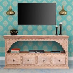 an entertainment center with a flat screen tv mounted on it's side, in front of a wallpapered background