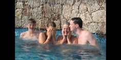 four people are in the pool and one person is covering his face with her hands