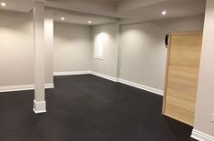 an empty room with white walls and black carpet