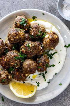 a white plate topped with meatballs covered in sour cream and garnished with parsley