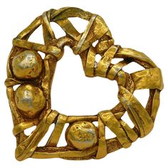 a gold brooch that is shaped like a circle and has four balls in it