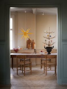 a dining room table and chairs with a christmas tree in the center surrounded by ornaments