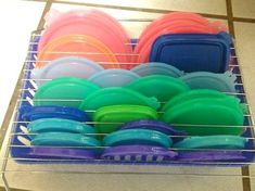 a rack filled with lots of different colored plastic plates and bowls on top of a tiled floor