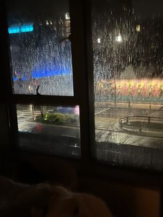 A photo of a rainy window Apartment Rain Aesthetic, Cozy Bed Rain, Rain Inside House, Comfy Bed Aesthetic Rainy Day, Rainy Night Bedroom Aesthetic, City View Apartment Night Window Rainy, Rainy Bedroom Window, Rainy Night In Bed, Rainy Apartment Aesthetic