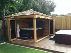 a wooden gazebo with a hot tub in the middle and green grass around it