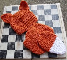 two knitted hats sitting on top of a checkered board