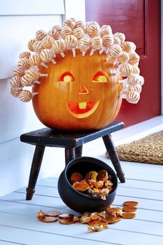 a pumpkin sitting on top of a chair next to a bowl filled with candy chips