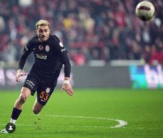 a man kicking a soccer ball on top of a field