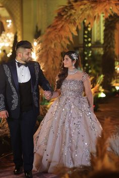 a man in a tuxedo and a woman in a wedding dress holding hands