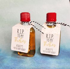 two small bottles with labels on them are sitting next to each other and tied together