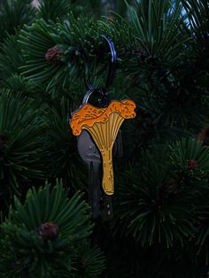 a keychain hanging from a pine tree with the shape of a fan on it