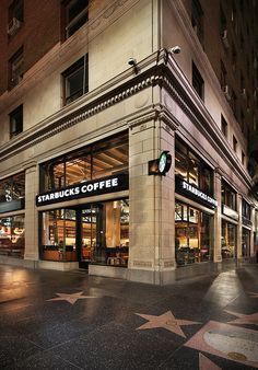 starbucks coffee is located on the corner of a city street at night with stars painted on the sidewalk