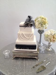 a three tiered cake sitting on top of a table next to two vases filled with flowers