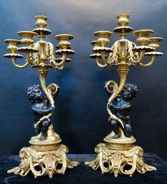 two golden candelabras sitting on top of a black table next to each other