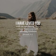 a woman walking through a field with mountains in the background and a bible verse written on it