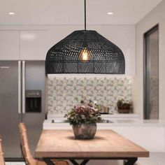 a dining room table with chairs and a light hanging over the kitchen island in front of it