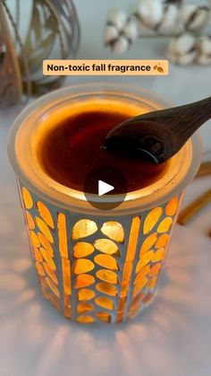 a candle with a spoon in it sitting on a table next to other candles and decorations