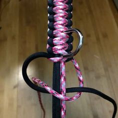 a pink and black rope is attached to a pole with a metal ring on it