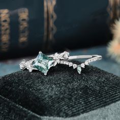 a close up of a ring on top of a black velvet surface with books in the background