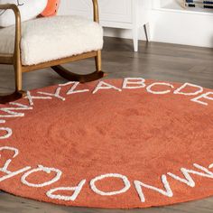 an orange rug with white writing on it in a living room next to a chair