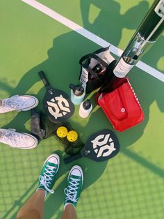 tennis shoes and equipment laid out on the court with people's feet propped up next to them