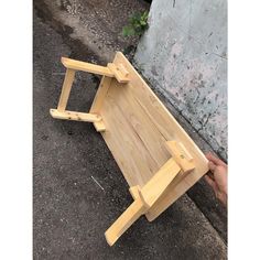 a person holding a small wooden table with two legs that are bent to the side