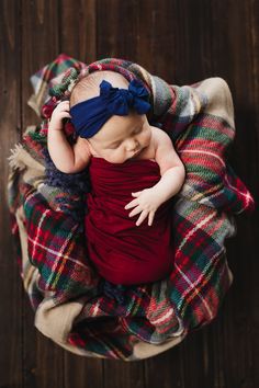 a newborn baby wrapped in a red wrap with the words born on it's head