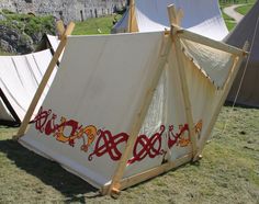 an old teepee tent with designs on it in the grass next to some tents