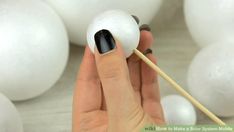 a hand holding a stick with some white balls in the background and black tips on it