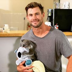 a man holding a koala and a stuffed animal in his hands while smiling at the camera