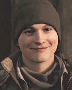 a man wearing a beanie and scarf smiling at the camera with his eyes wide open