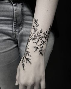 a black and white photo of a woman's arm with leaves on it