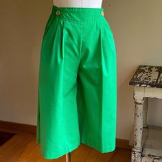 Kelly green culottes with a yoke front, double side button closure, front pleats, wide back elastic waist, hip pockets. Zero flaws, no signs of wear. 65/35 poly/cotton blend.  By Coqui and tagged a size 7.  Freshly hand washed and ready to wear. Please use the measurements for fit.   Taken flat  Waist 12.5- 14.5"  Hip 20"  Rise 13"  Inseam 14"  Leg opening 14.5"  Because sizing is not universal among makers or across decades, size numbers are just a starting point. To ensure proper fit, you must measure and compare to a garment that fits you well. There really is no other way. Please be aware, if you need an exact color match, that colors vary from monitor to monitor. I do my best to write accurate descriptions, and I photograph in natural daylight. If you need additional information pleas Green Culottes, Kelly Green, Vintage 70s, Short Outfits, Color Matching, Bermuda Shorts, Elastic Waist, Ready To Wear, Cotton Blend