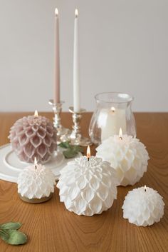 some white candles are sitting on a table