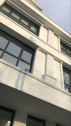 a white building with black windows and a clock on the side of it's face