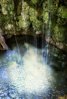 the water is flowing down from the rocks into the pool with waterfalls in it