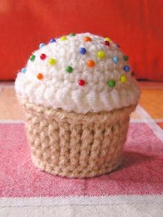 a crocheted cupcake with white frosting and multi colored sprinkles