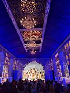 a group of people standing in front of a blue lit room with chandeliers hanging from the ceiling